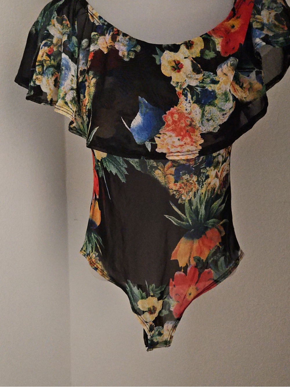 black bodysuit features a vibrant tropical floral print